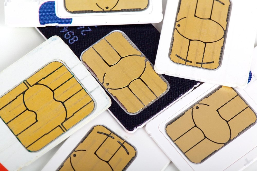 A pile of SIM cards, gold contact chips facing up